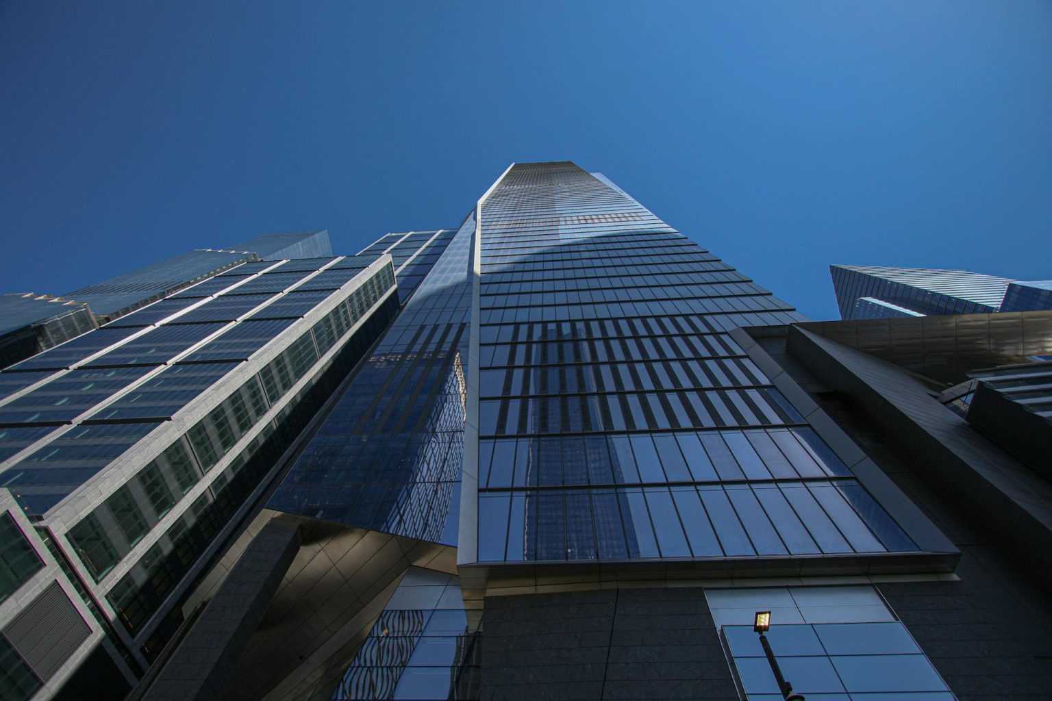 Dramatic low-angle view of skyscrapers against a clear blue sky in New York City.