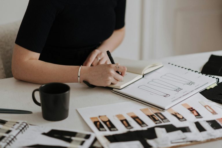 Female designer working on fashion sketches in a creative studio environment.